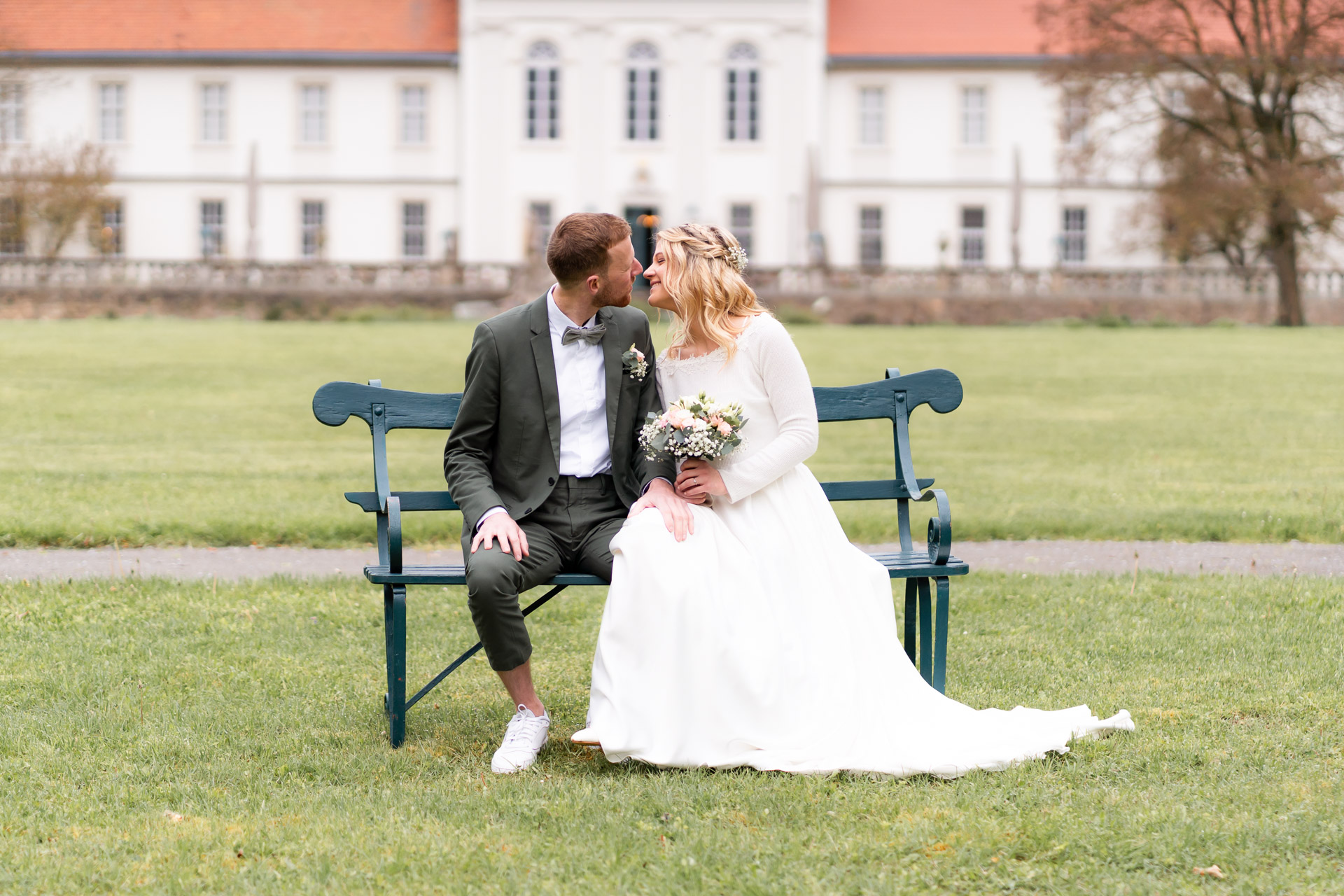 Sarah und Benedikt auf einer Bank vor einem Schloss